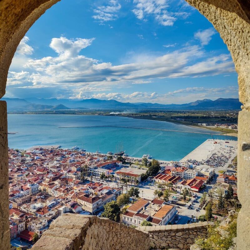 Captivating view of Nafplio town and coast through a historic stone archway.